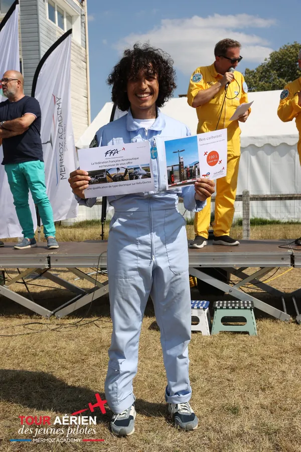 Amine sur la scène de Jonzac, en combinaison de vol, tenant le diplôme remis par la FFA